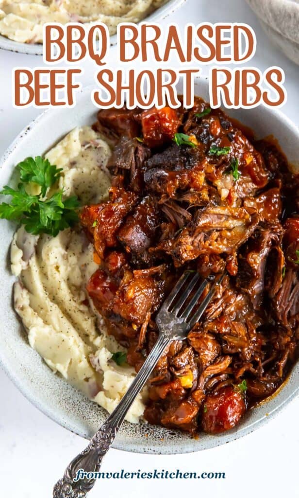 A top down shot of a fork resting in a bowl of short ribs in a saucy bbq mixture and mashed potatoes with text.