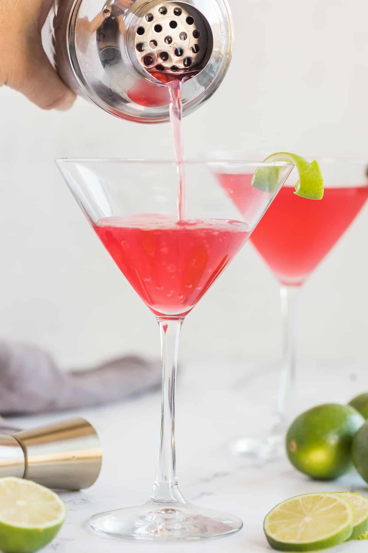 A cosmopolitan pouring out of a cocktail shaker into a martini glass.