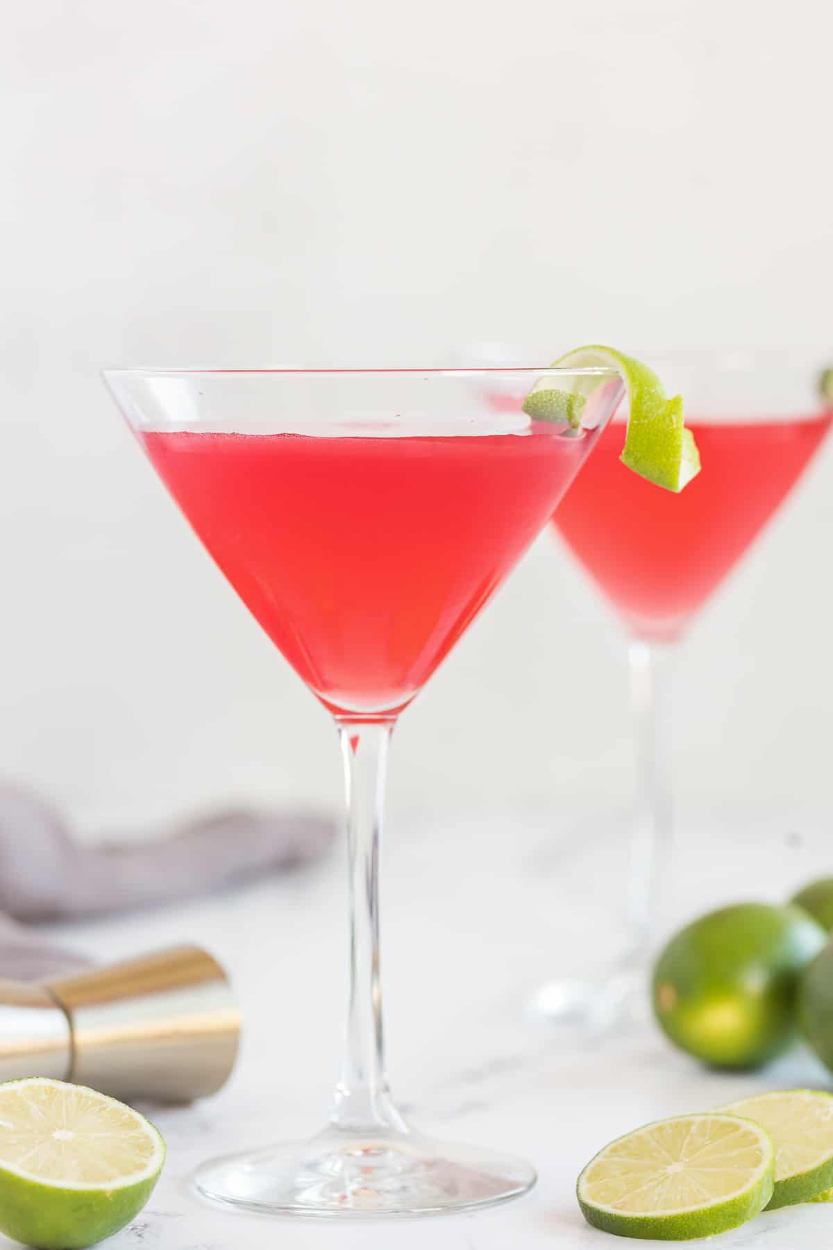 Two cosmos in martini glasses garnished with a twist of lime on the rim.