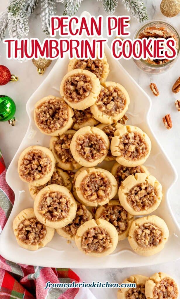 Pecan Pie Thumbprint Cookies on a Christmas tree shaped platter surrounded by ornaments with text.