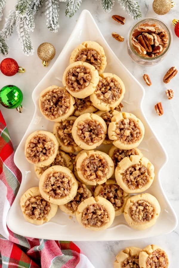 Pecan Pie Thumbprint Cookies on a Christmas tree shaped platter surrounded by ornaments.