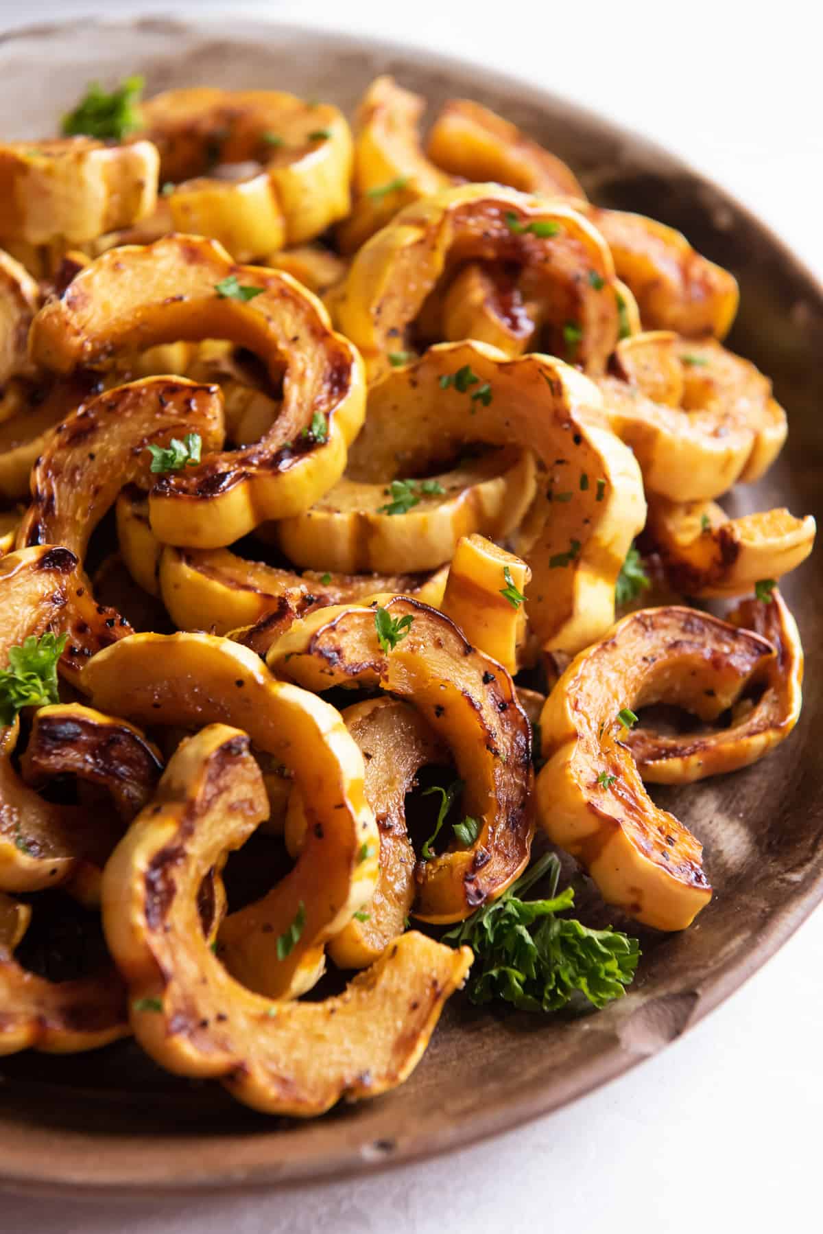 Roasted delicata squash piled on a wooden platter.