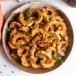 A top down shot of roasted delicata squash on a round wooden platter.