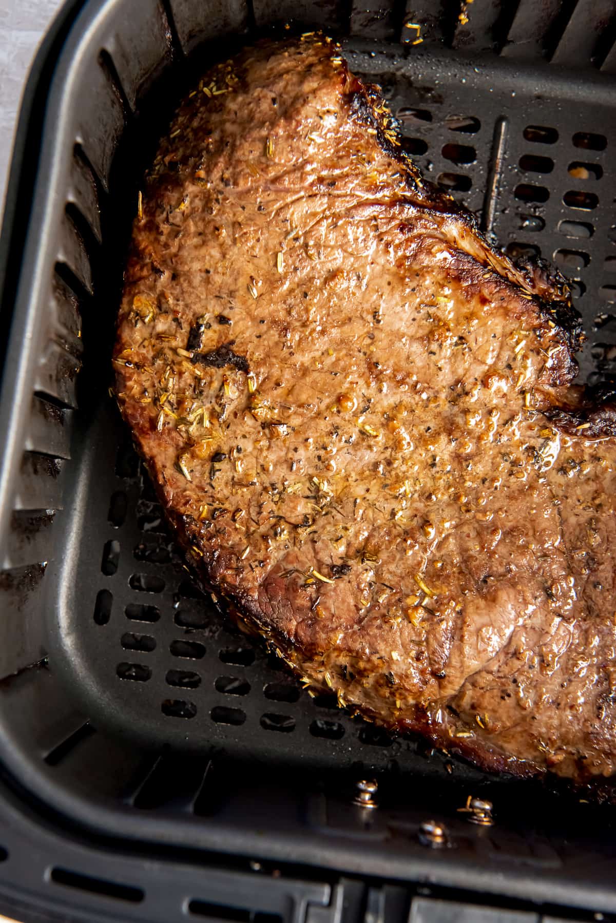 A top down shot of a cooked London Broil in an air fry basket.
