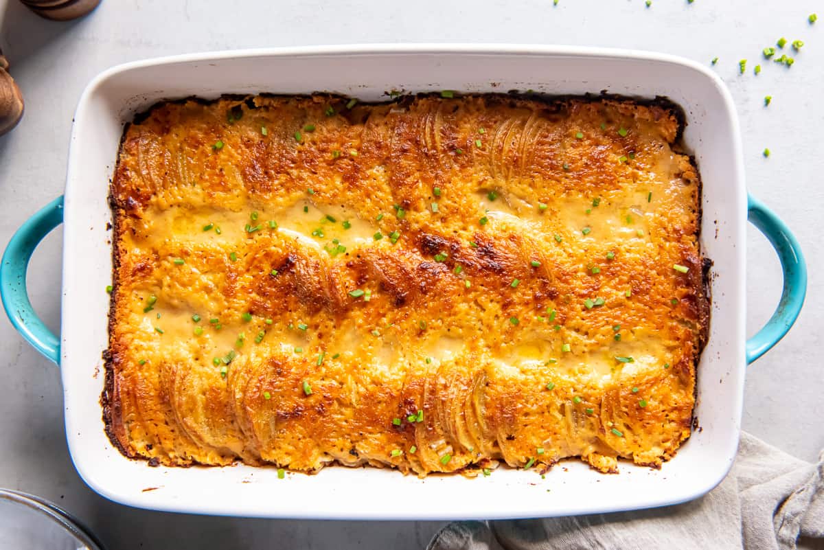 A top down shot of au gratin potatoes in a baking dish with blue handles.