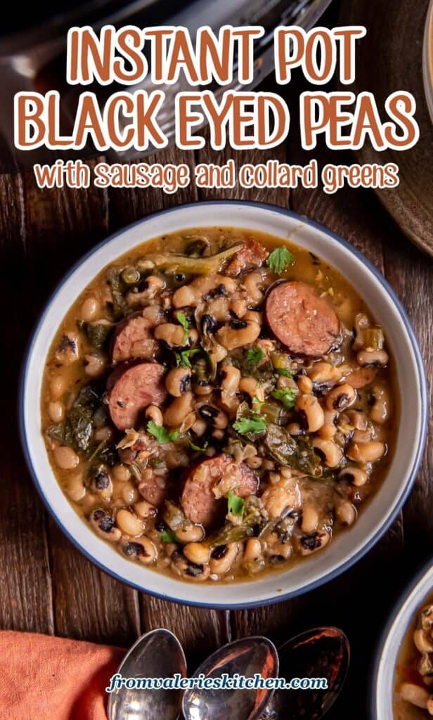 A top down shot of a bowl filled with black eyed peas and sausage with collard greens on a dark wood board with text.