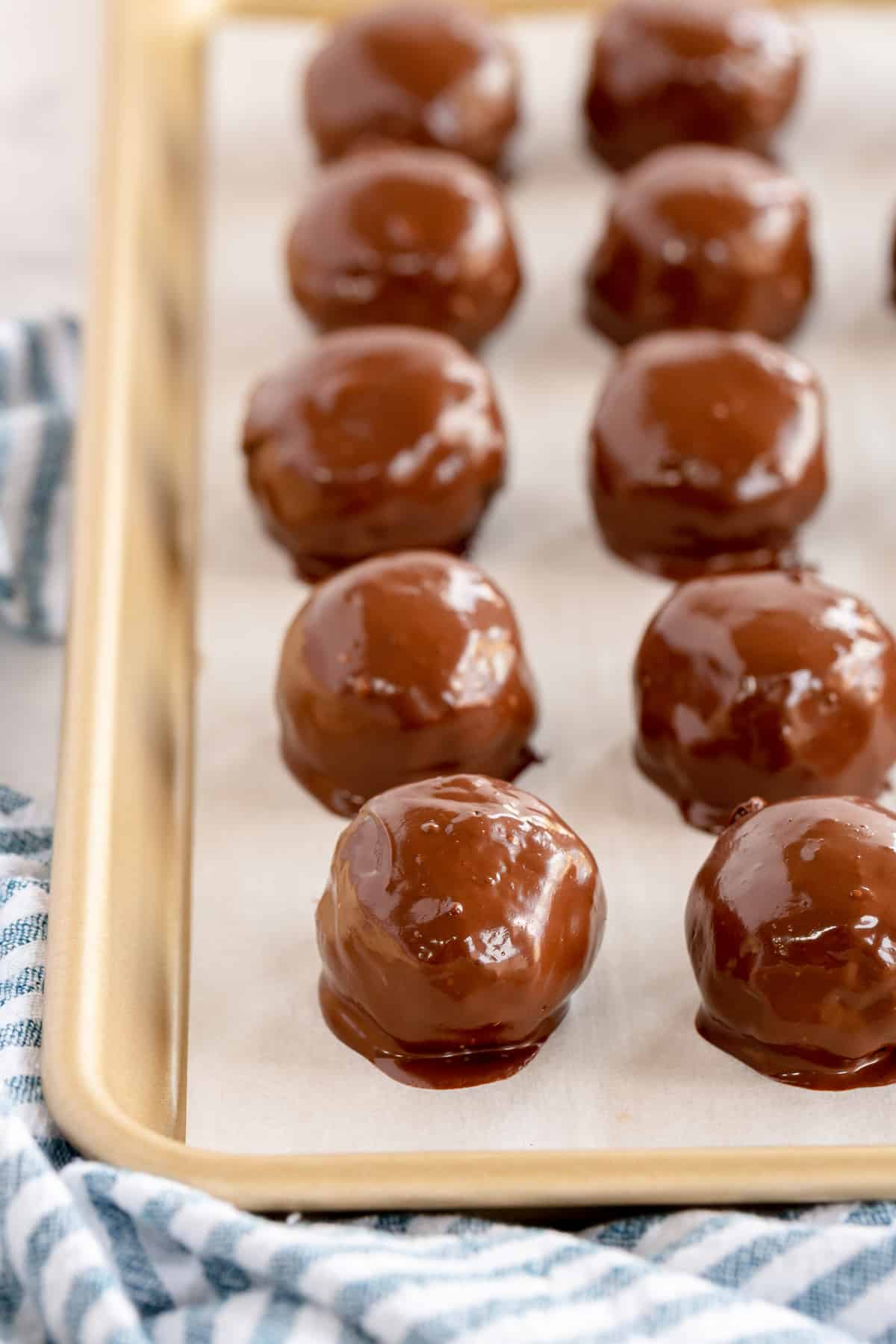 Glossy chocolate dipped bon bons on a parchment paper lined baking sheet.