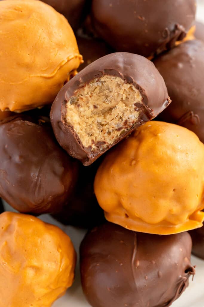 A close up of a chocolate coated bon bon with a bite missing on top of a stack.