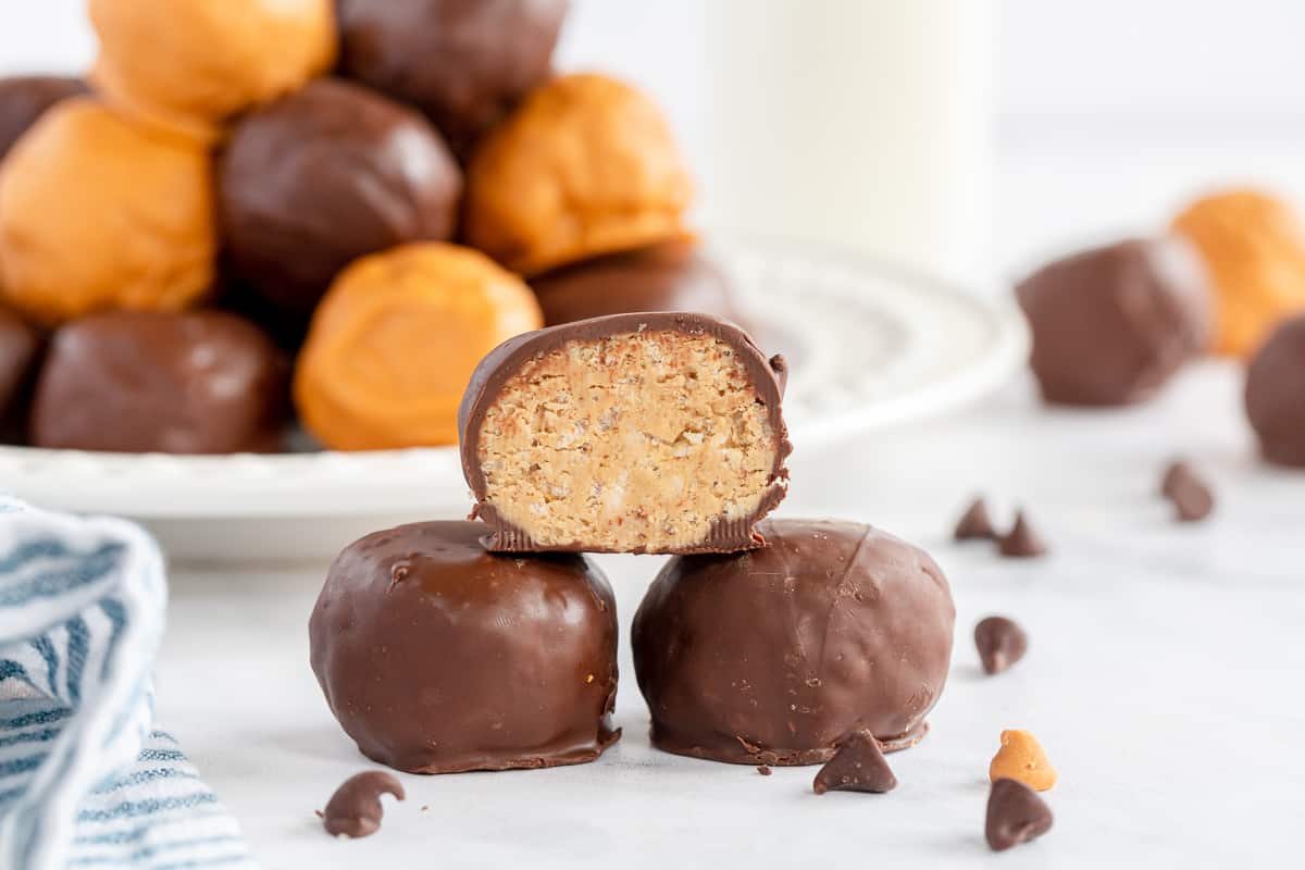 A chocolate coated bon bon with a bite missing stacked on top of two others.