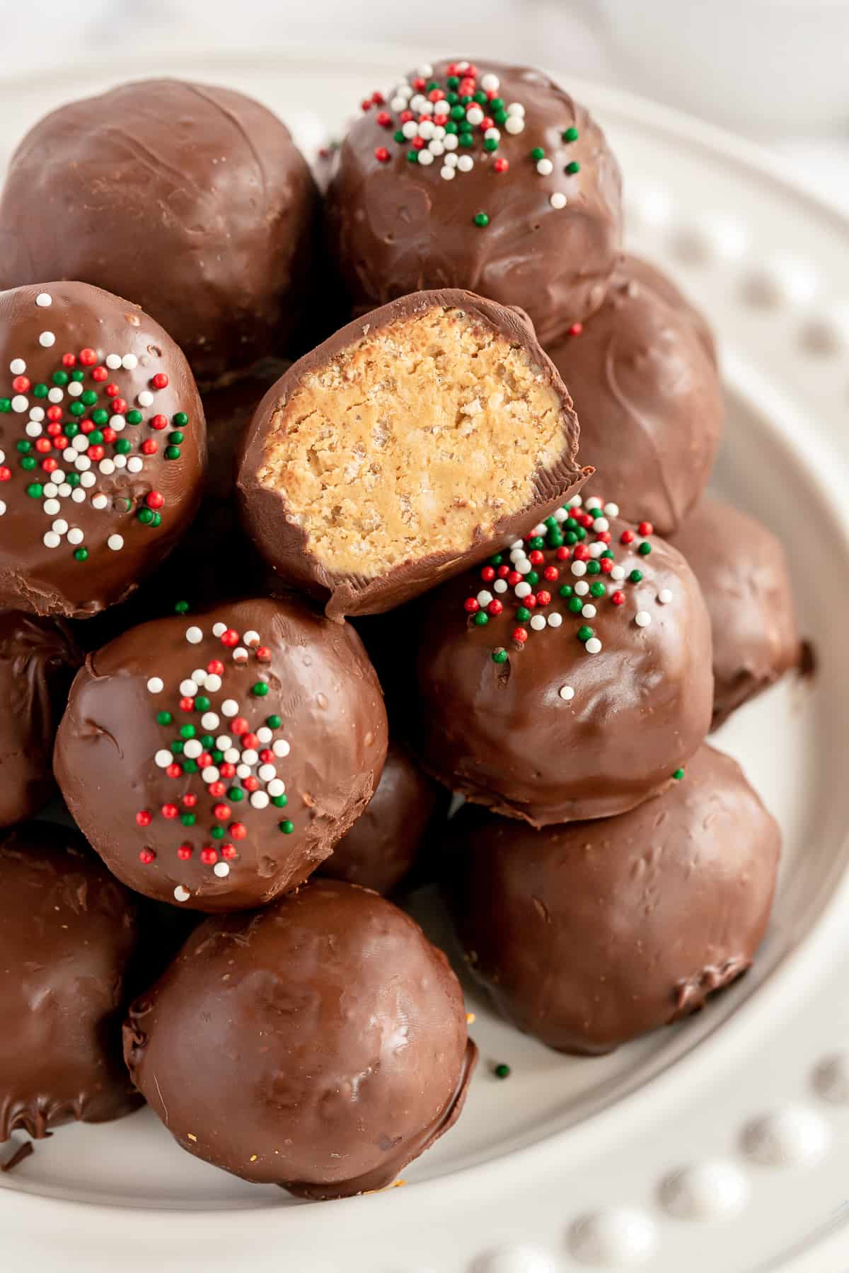 Chocolate Peanut Butter Bon Bons with red and green Christmas sprinkles stacked on a white plate.