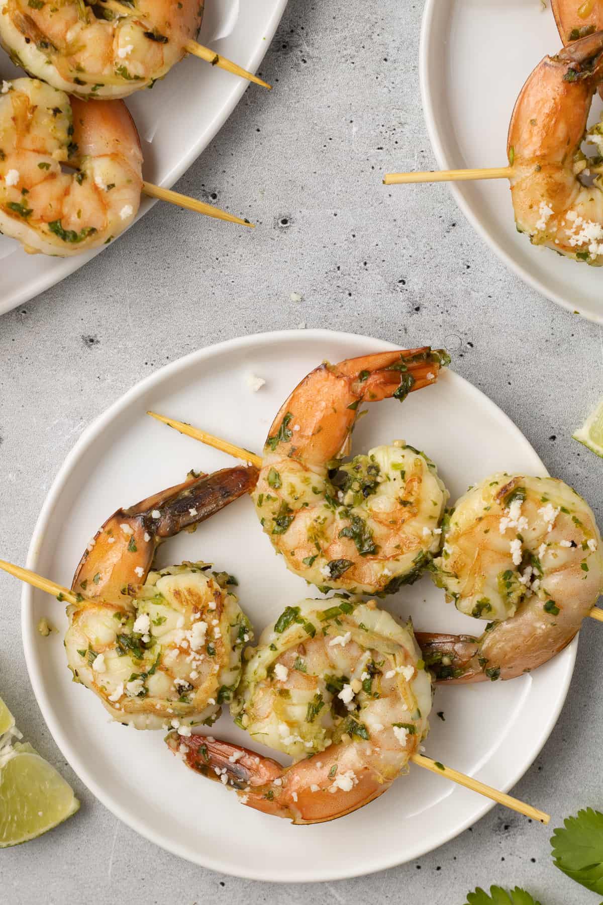Two shrimp skewers on a small white plate.