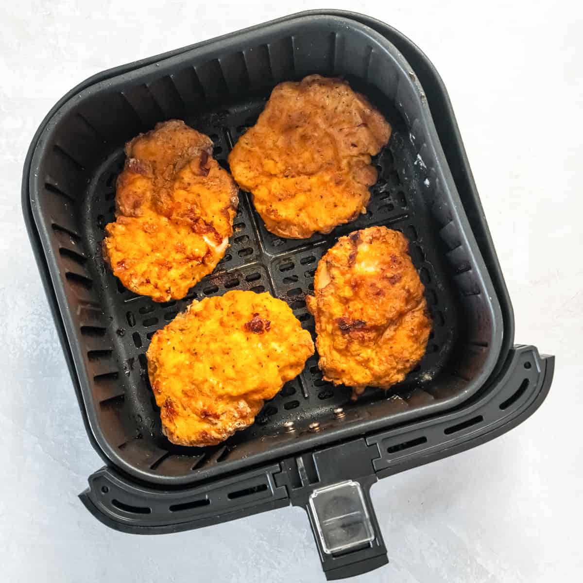 Cooked breaded chicken in an air fryer basket.