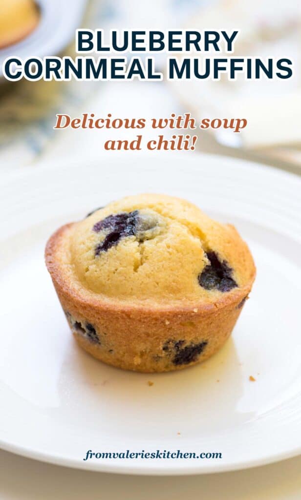 A cornmeal muffin with blueberries on a white plate with text.