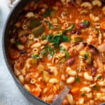 A top down shot of a large pot filled with minestrone soup with chicken and pasta.