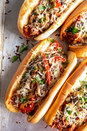 A top down shot of four Italian Sausage Sandwiches on a baking sheet.