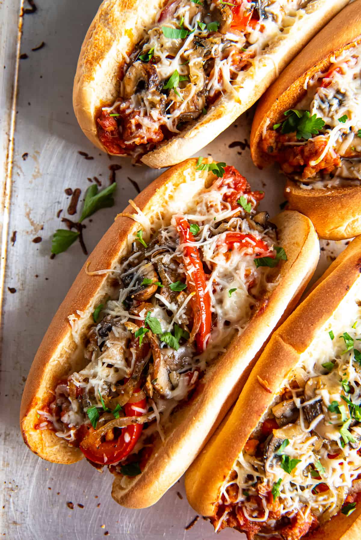 A top down shot of four Italian Sausage Sandwiches on a baking sheet.