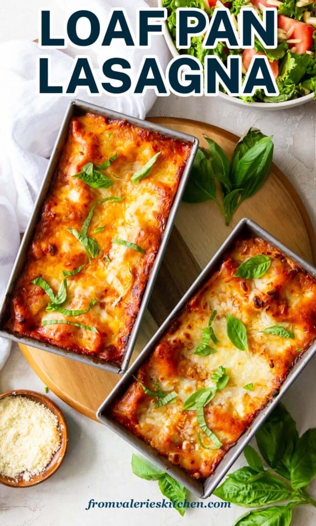 A top down shot of lasagna in two loaf pans with fresh basil and a small bowl of Parmesan around them with text.