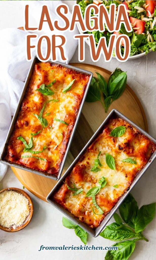 A top down shot of lasagna in two loaf pans with fresh basil and a small bowl of Parmesan around them with text.