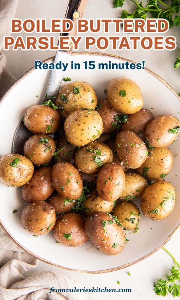 A top down shot of parsley potatoes in a white bowl with fresh parsley around it with text.