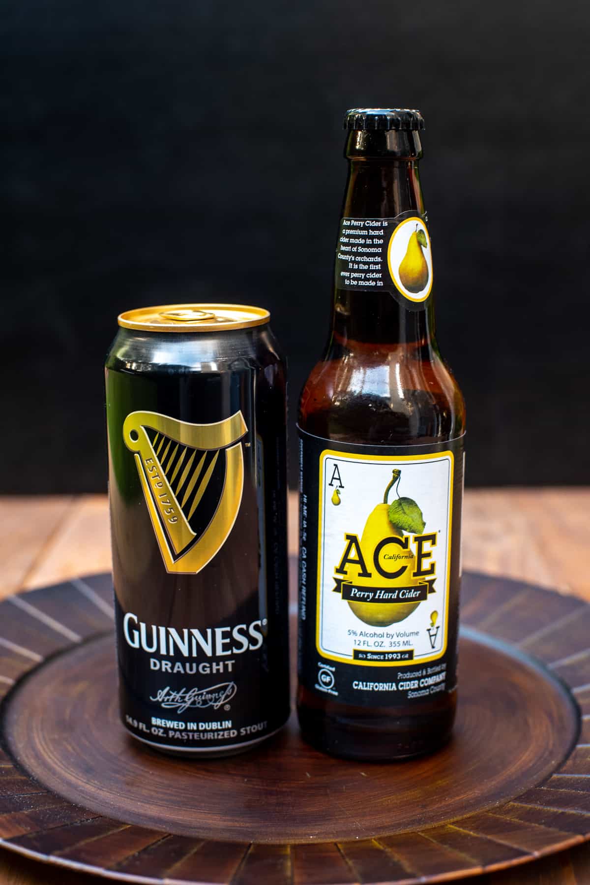 A can of Guinness Draught and a bottle of Ace Pear Cider on a brown platter.