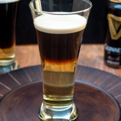 A half Guinness and half hard cider Snakebite Drink in a beer glass on a brown platter,