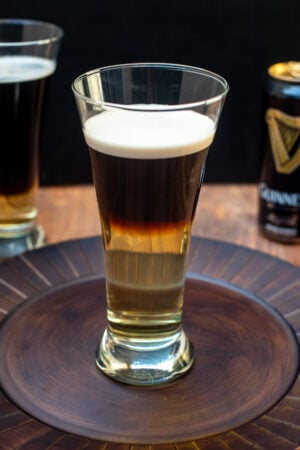 A half Guinness and half hard cider Snakebite Drink in a beer glass on a brown platter,