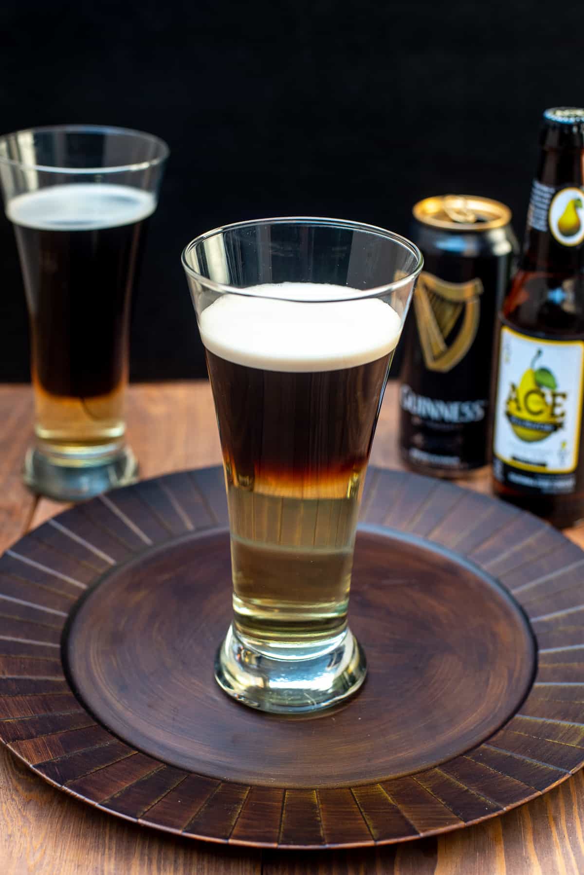 A half Guinness and half hard cider Snakebite Drink in a beer glass on a brown platter,