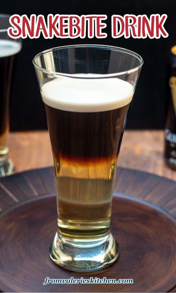 A half Guinness and half hard cider Snakebite Drink in a beer glass on a brown platter with text.