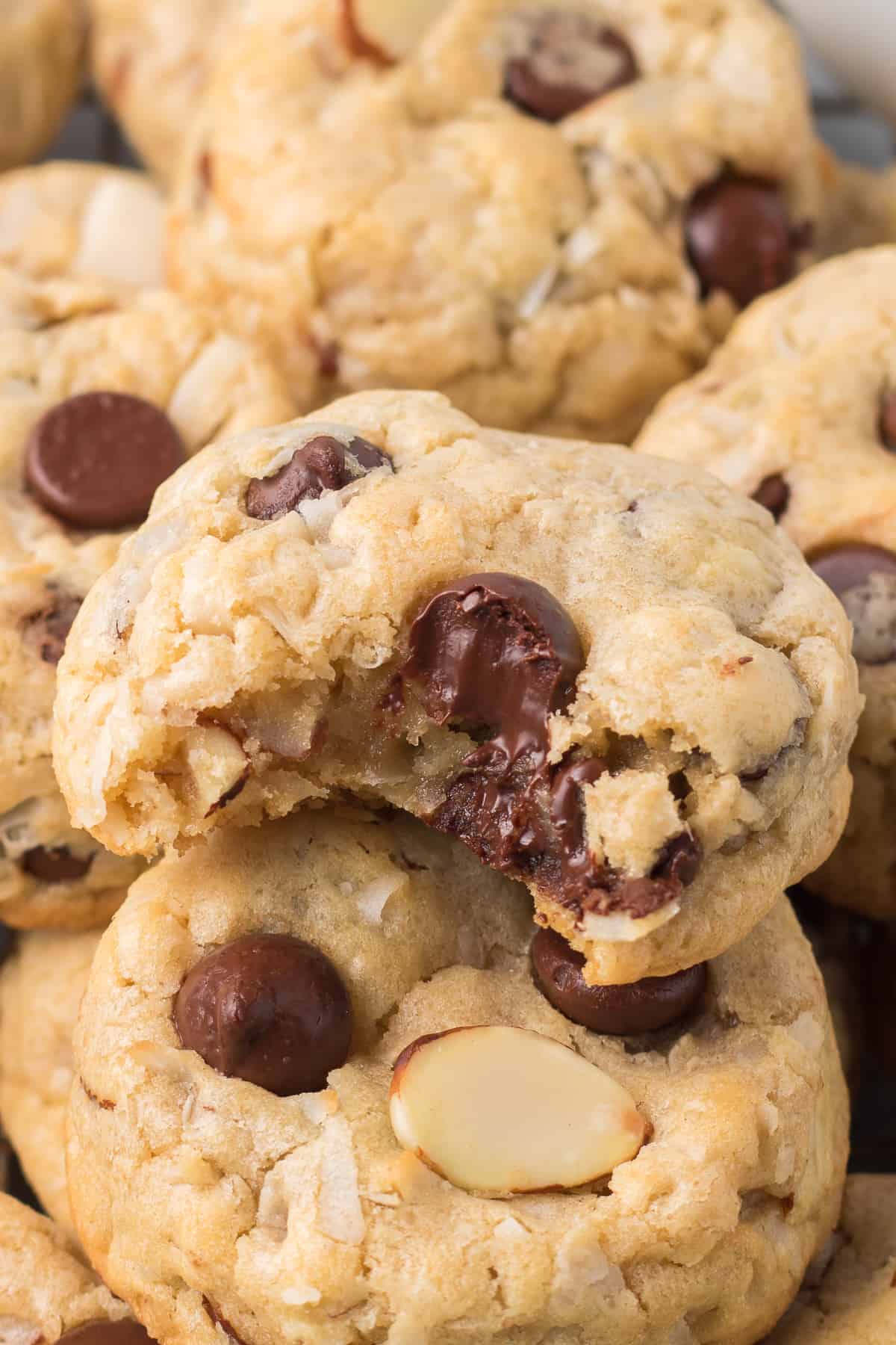 A cookie with a bite missing on top of a pile of other cookies.