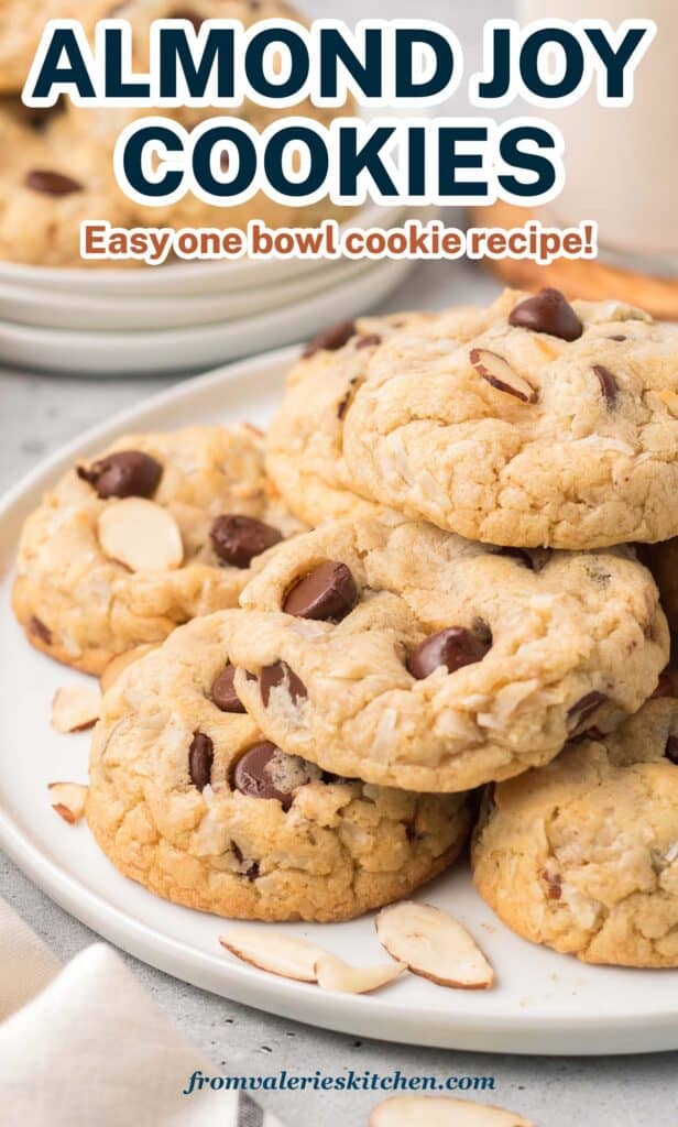 A pile of Almond Joy Cookies on a white plate with smaller plate and glass of milk in the background with text.