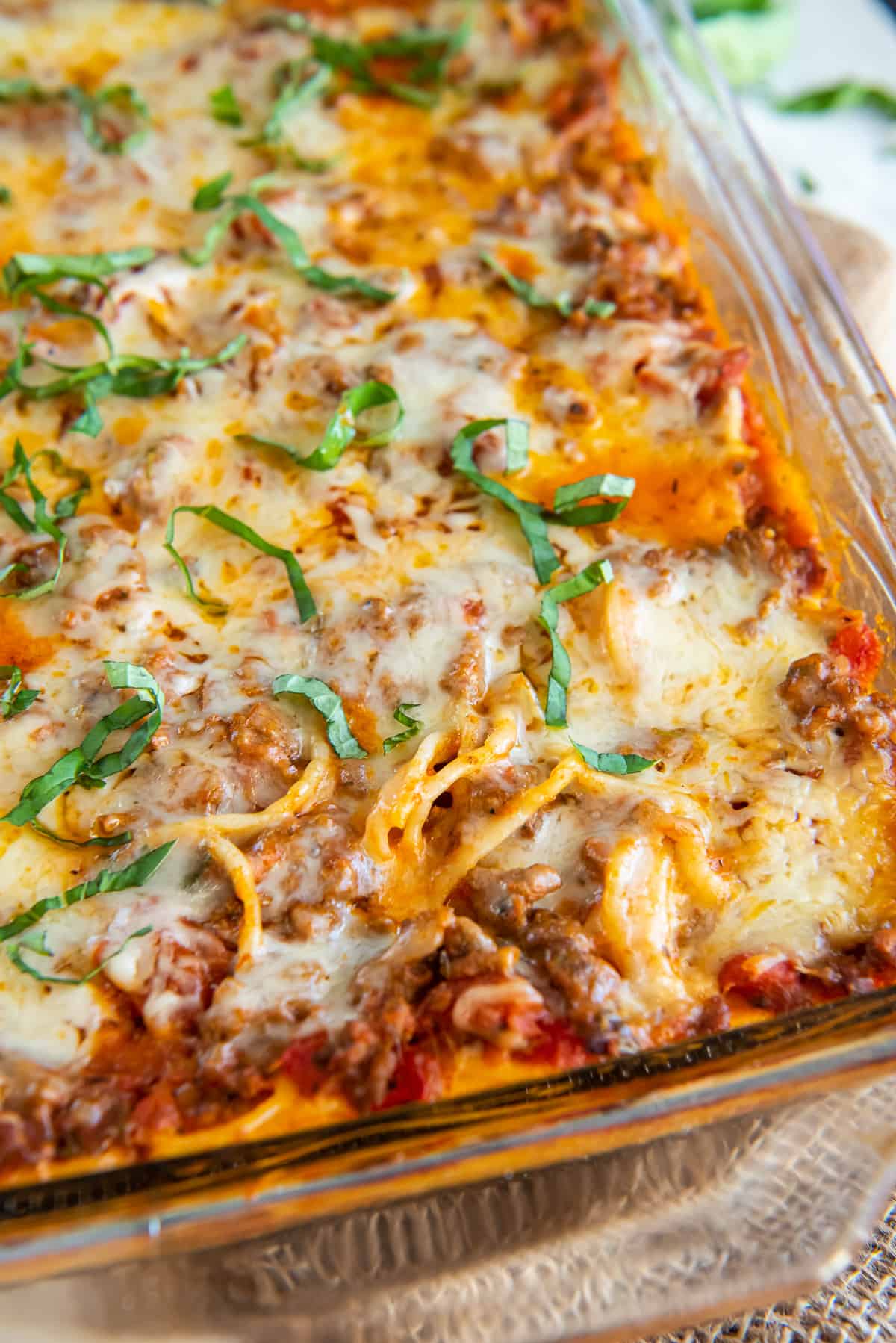 A closeup of spaghetti casserole with ricotta cheese in a baking dish.