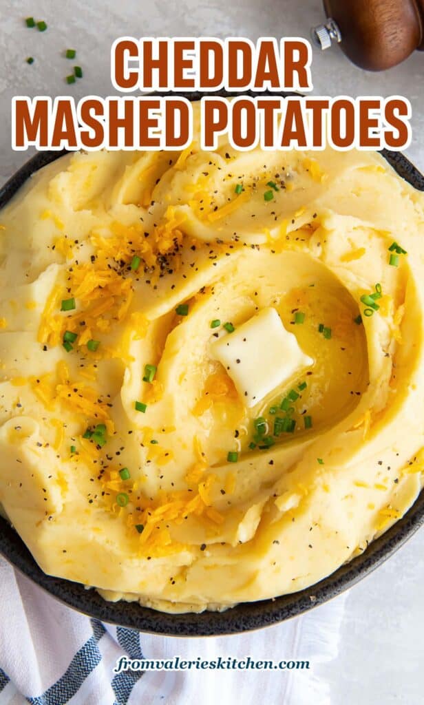 A top down shot of cheddar mashed potatoes topped with pepper and butter with text.