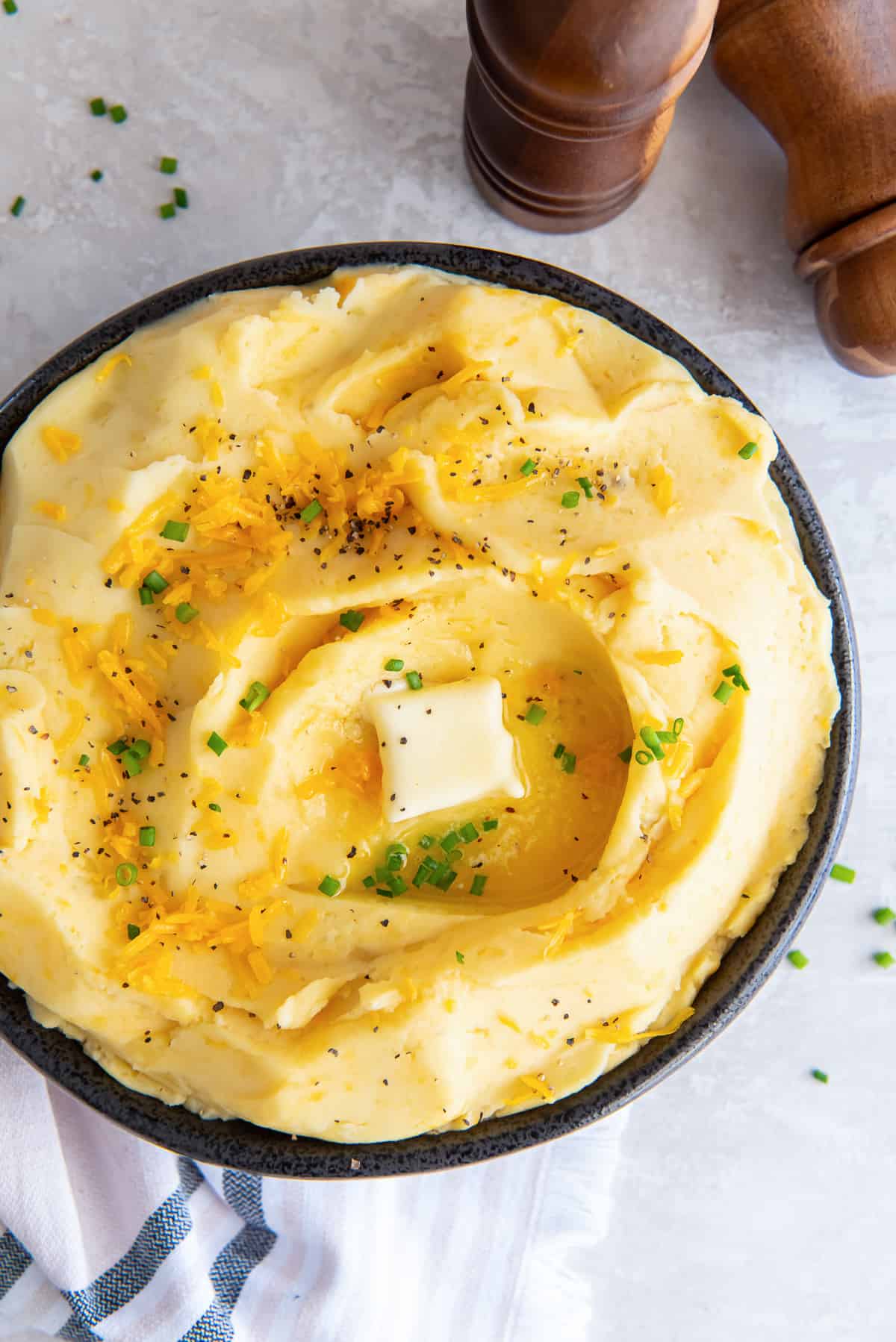 A top down shot of cheddar mashed potatoes topped with pepper and butter.