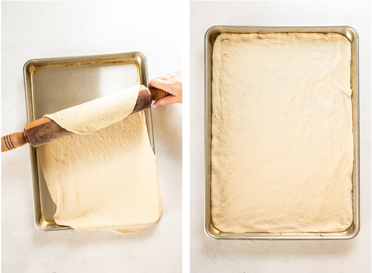 Pizza dough on a rolling pin being placed on a large sheet pan.