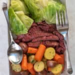 Corned beef, cabbage, carrots and potatoes in a white serving dish.