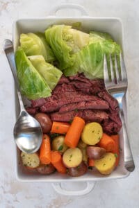 Corned beef, cabbage, carrots and potatoes in a white serving dish.