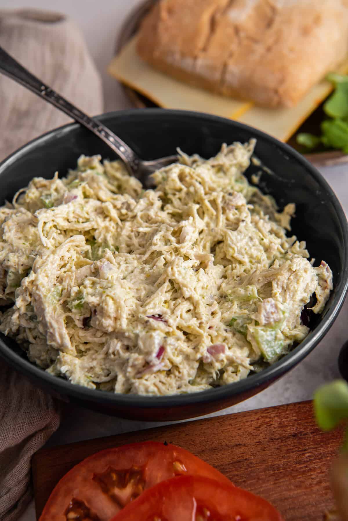 Pesto chicken salad in a black bowl with a spoon.