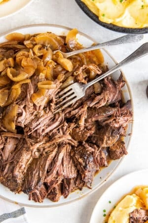 A top down shot of a plate of shredded green chile beef with onions.