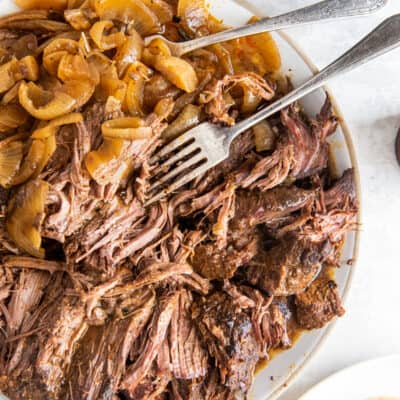 A top down shot of a plate of shredded green chile beef with onions.