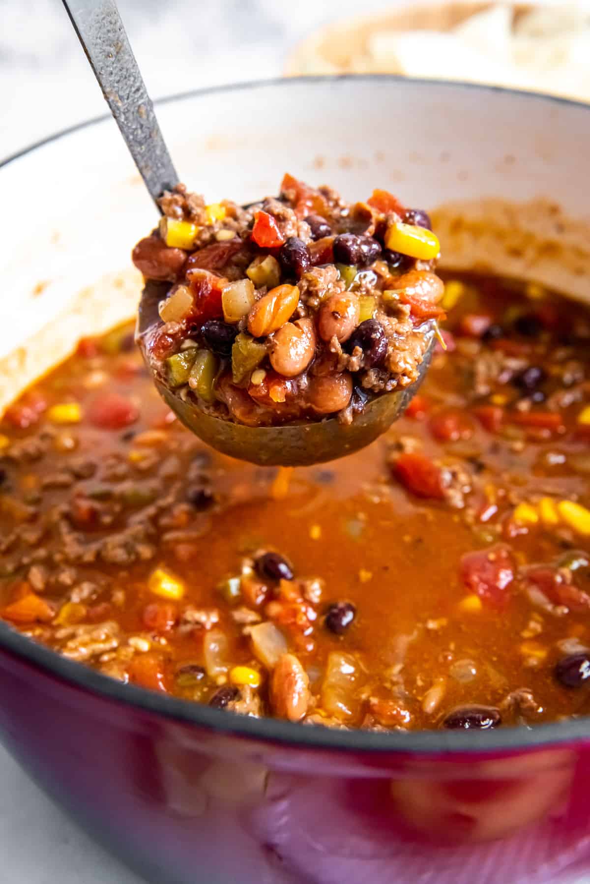 A ladle filled with a scoop of taco scoop hovering over a pot.