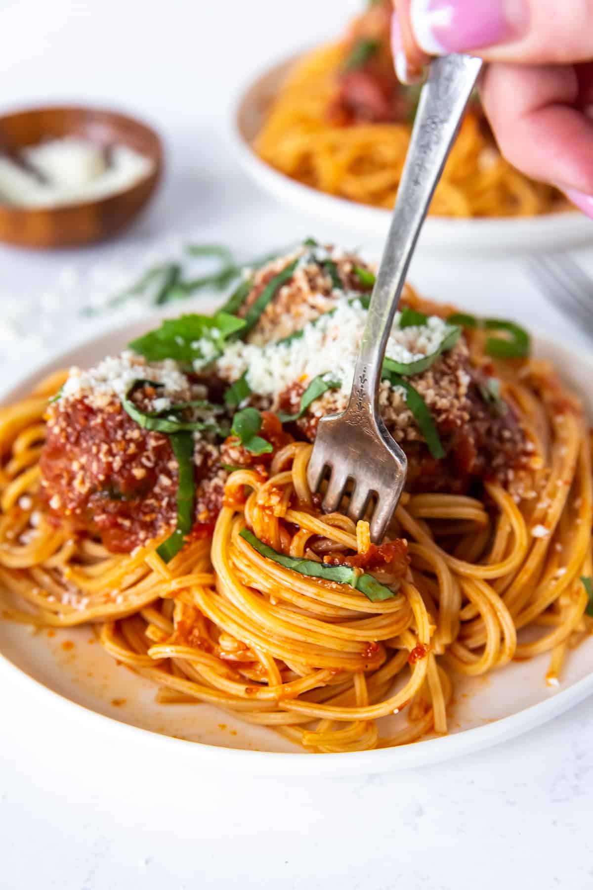 A fork twirling spaghetti on a white plate.