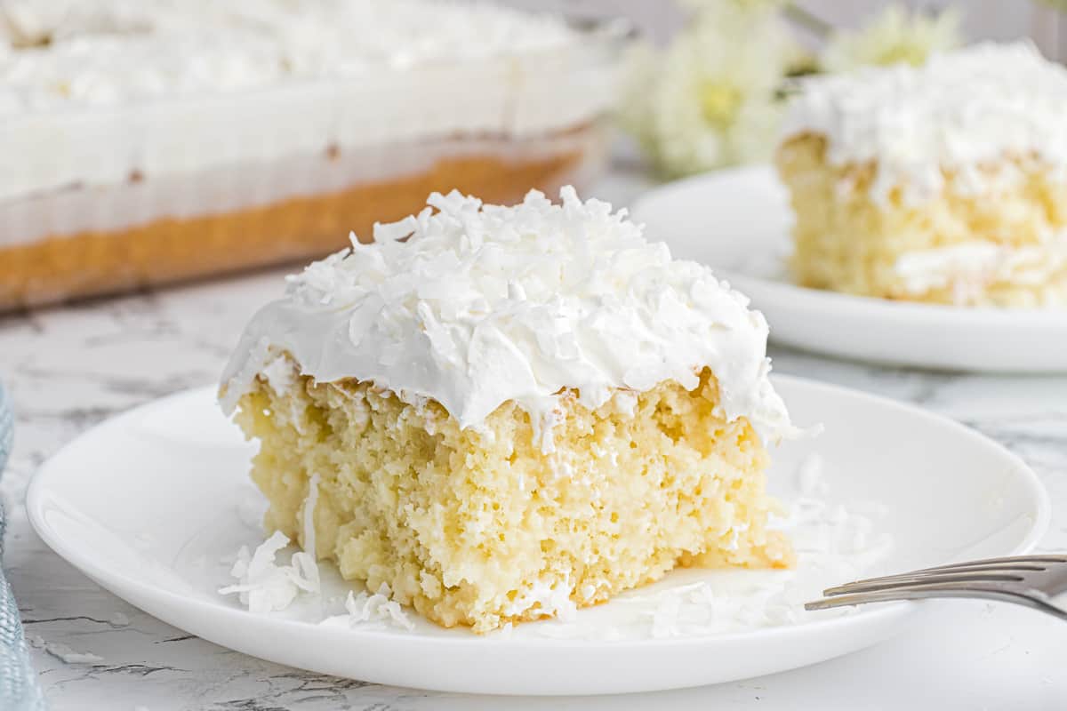 A slice of coconut poke cake on a white plate.