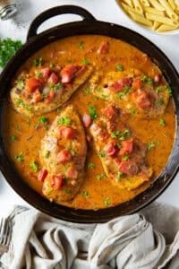 A top down shot of chicken in a tomato cream sauce in a cast iron skillet.