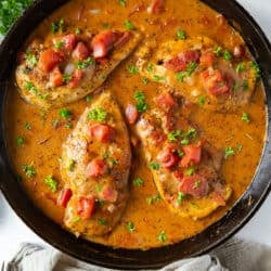 A top down shot of chicken in a tomato cream sauce in a cast iron skillet.