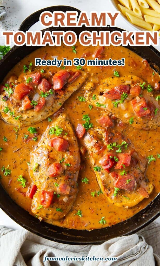 A top down shot of chicken in a tomato cream sauce in a cast iron skillet with text.