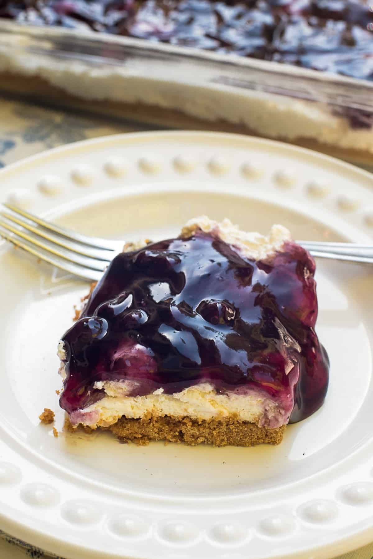 A slice of cheesecake with blueberry topping on a plate.