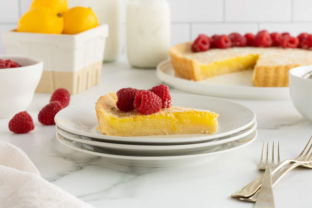 A plate with a slice of lemon tart on a kitchen counter.