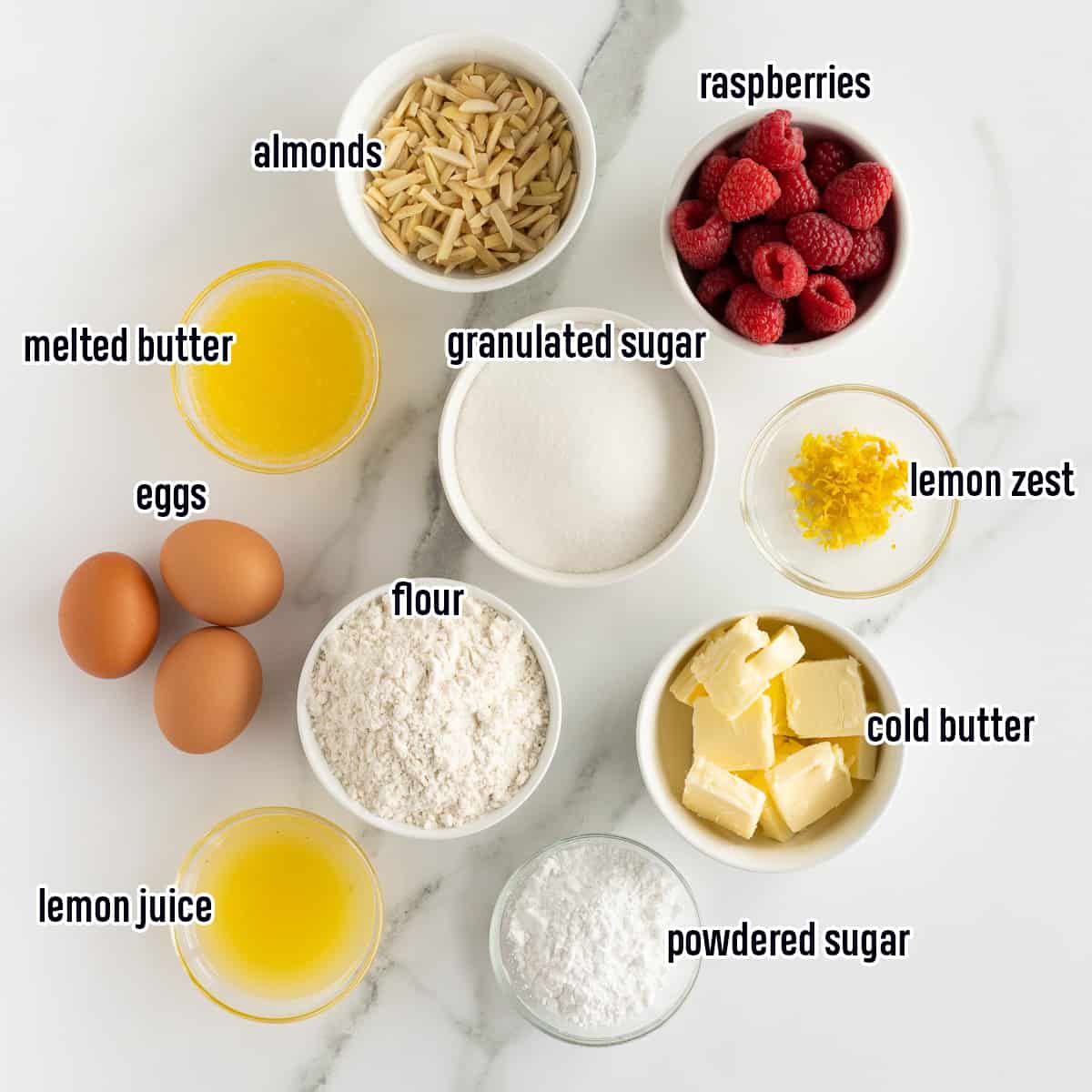 Lemon juice, almonds, flour, sugar and other ingredients in bowls with text. 