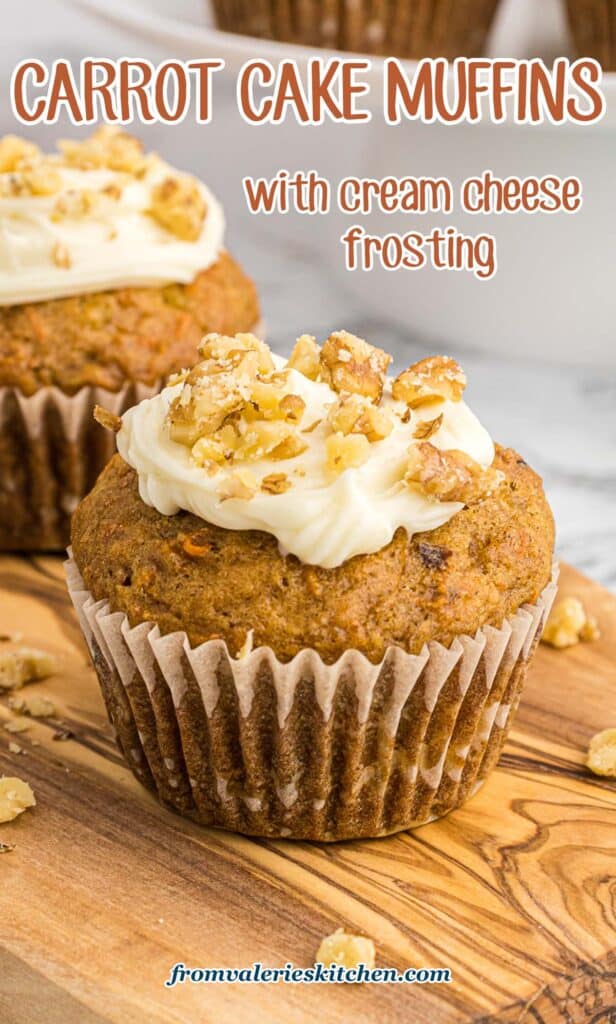 Two carrot cake muffins on a wood board with text.