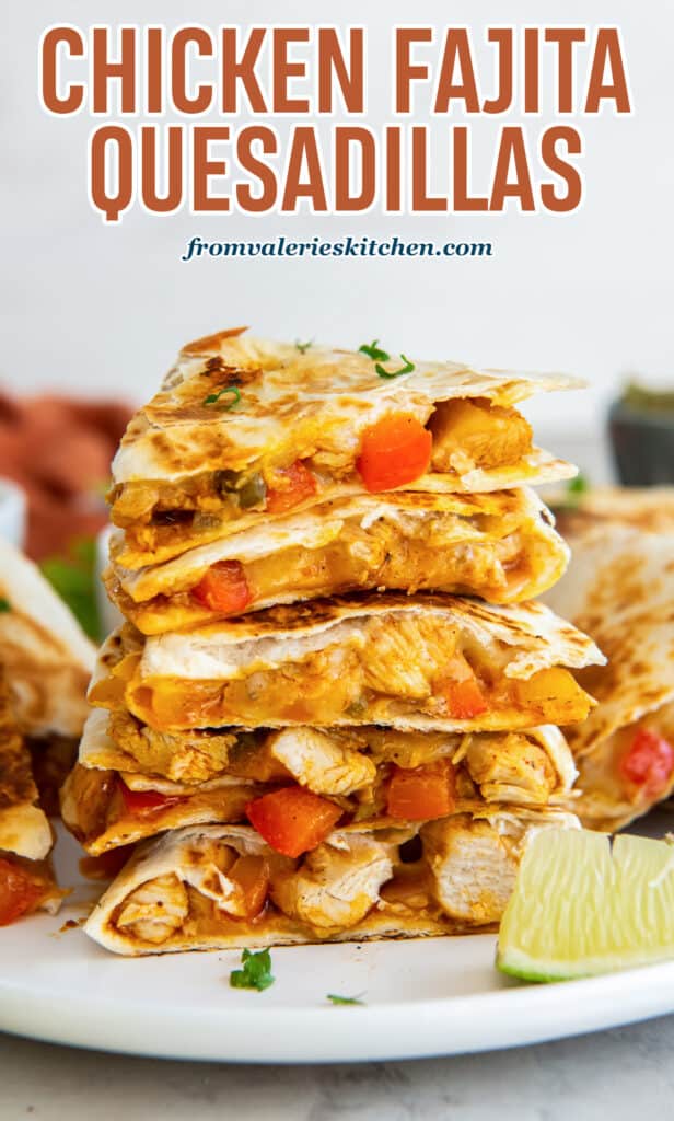 Wedges of chicken fajita quesadillas stacked on a white plate with a lime wedge with text.